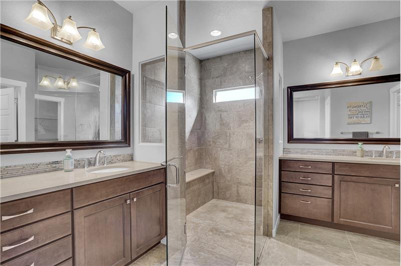 The Primary Spa Bathroom features tiled floors, a dual sink vanity, framed mirror, and tiled shower