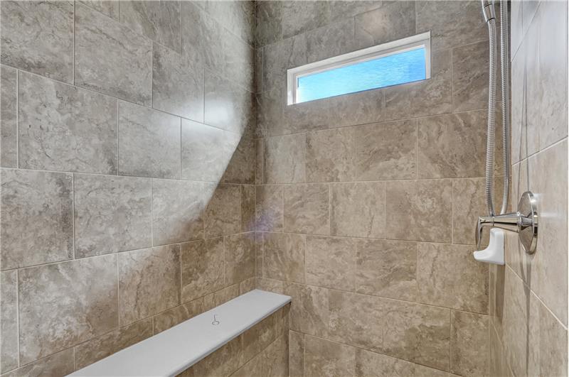 Floor to ceiling tiled shower with Schluter drainage system and built-in bench