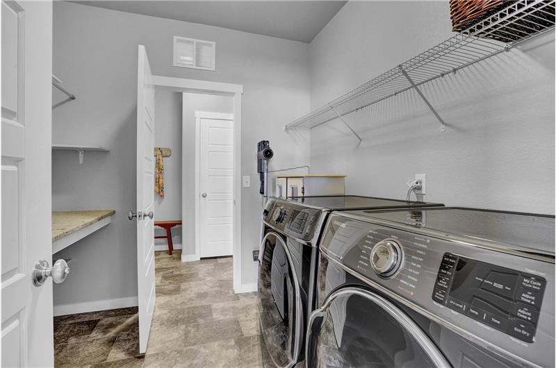 Main level Laundry Room with shelf,  folding table, and pass thru to the Mud Rm with garage access