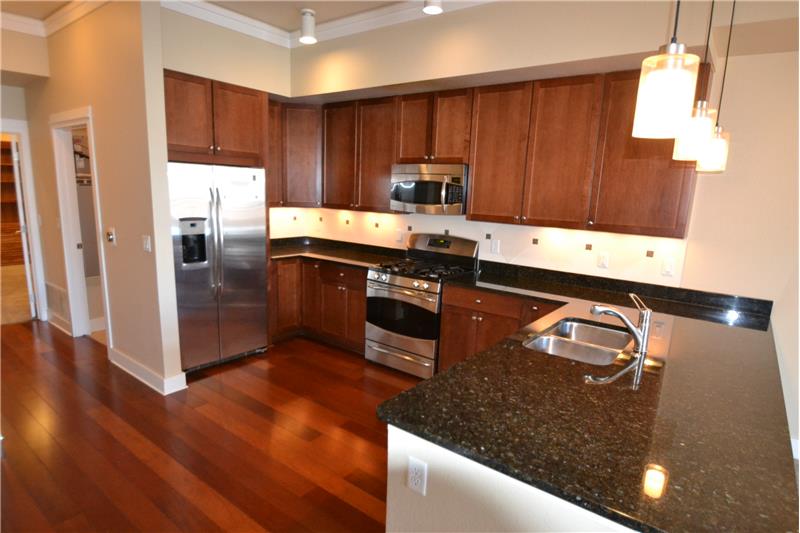 Kitchen has stainless appliances, hardwood floor and granite countertops