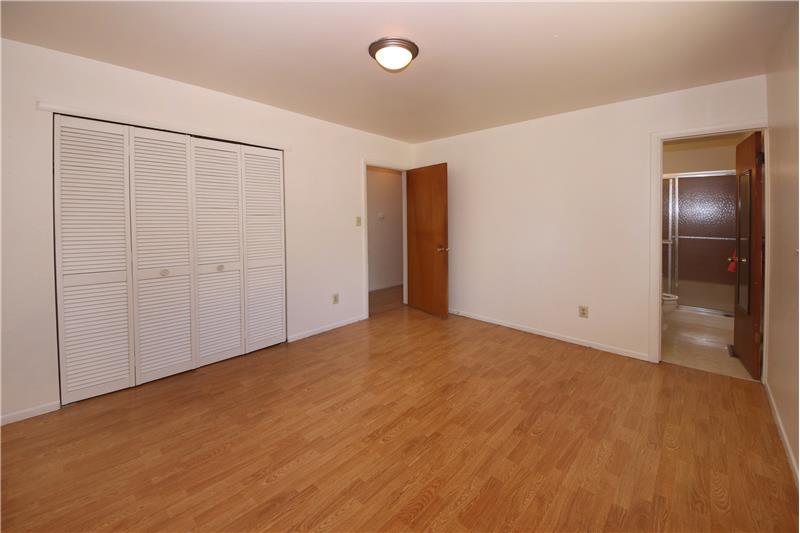 Master bedroom with hardwood flooring and an adjoining 3/4 bath