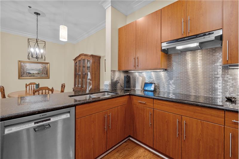 Kitchen features hardwood floors, pendant lights, recessed lights, under-cabinet lights, crown molding