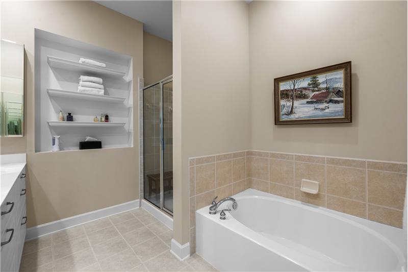 Primary bathroom a step in shower and separate bathtub both with tile surround + a private water closet