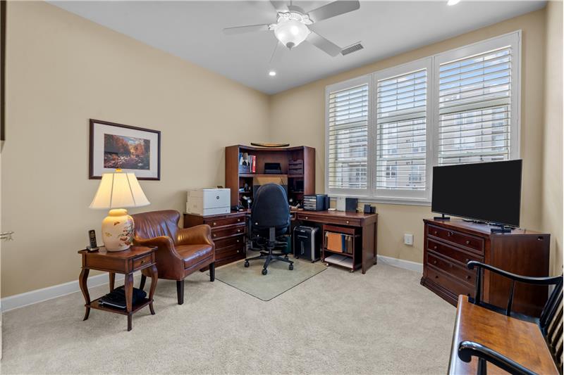 Second bedroom, currently used as a home office features plantation shutters, recessed lights + fan with light