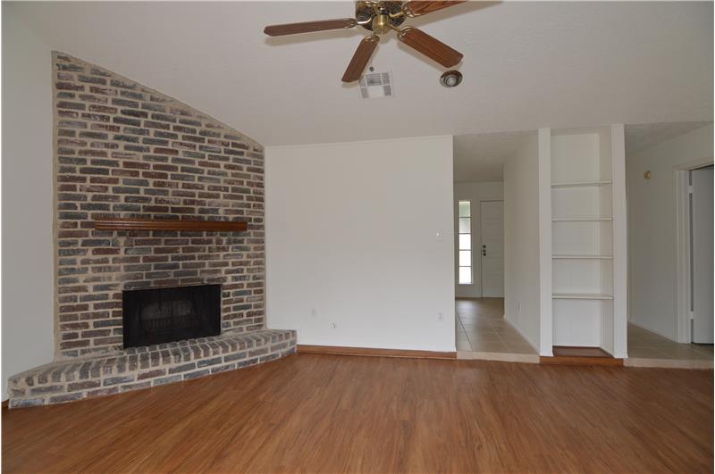 Family Room with a brick corner fireplace and new wood laminate flooring.
