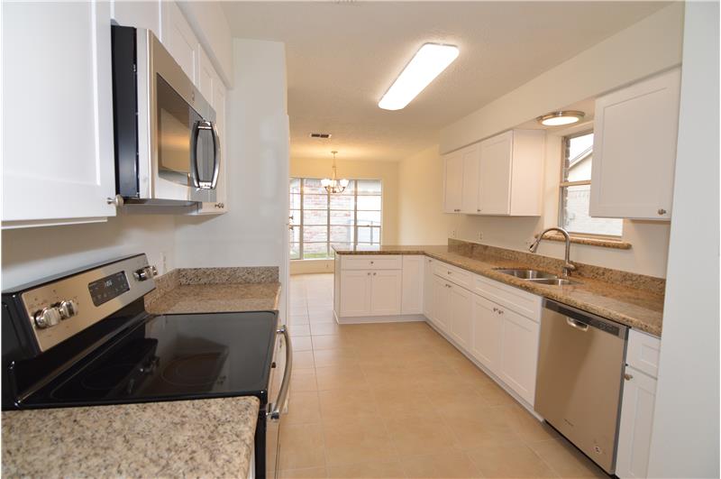 Kitchen with new granite counters, new stainless steel appliances, and brand new white cabinets.