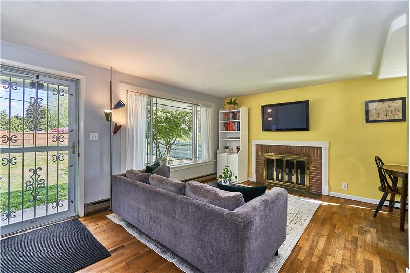 Cozy, Light and Bright Living Room with Hardwood Floors, Newer Vinyl Windows and Brick Surround Wood Burning Fireplace.