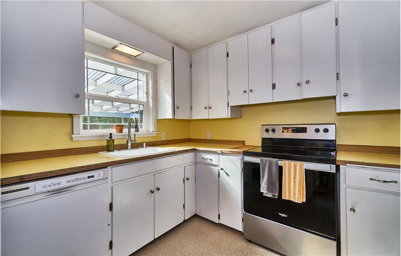 White Cabinets, Garden Window and Stainless Steel Flat Top Stove and Refrigerator.