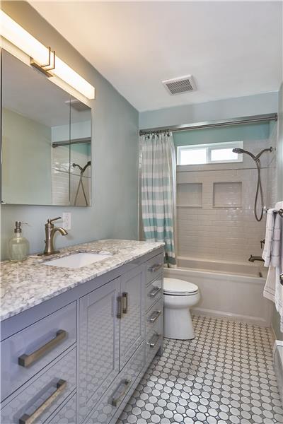 Recently Remodeled Bathroom with Marble Countertop, Custom Cabinets, Tile Floor and Tile surround shower/bath.