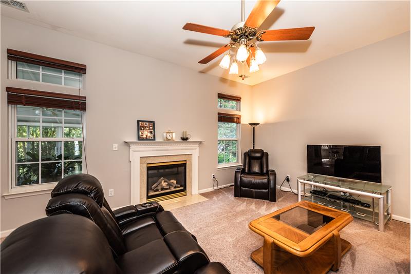 Great room has gas log fireplace with decorative mantel flanked by windows overlooking the private back yard.