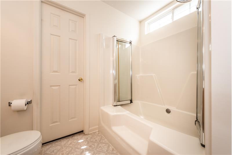 Nice-sized soaking tub/shower in owner's en-suite bathroom with transom window adding natural light.