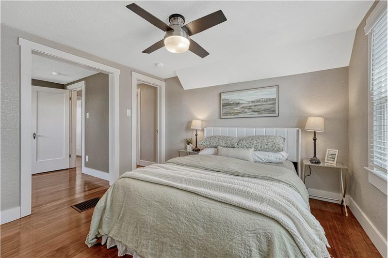 Primary bedroom with hardwood flooring, ceiling fan, and adjoining retreat