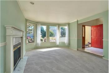 Large Formal Living Room with Tile Surround Gas Fireplace, Chair Rail and View of the Foyer.