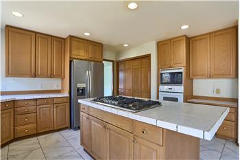 ovely Kitchen with Pantry, Center Island with Gas Stove. Tile Countertops and Tile Flooring