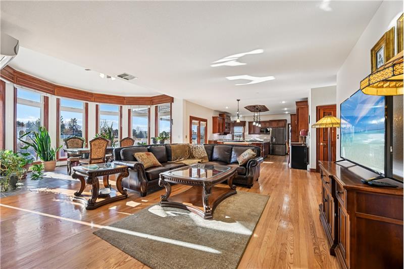 Reverse view of family room with kitchen beyond and eating area in bow window