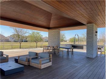Community area with outdoor kitchen and seating by the trails near this home.