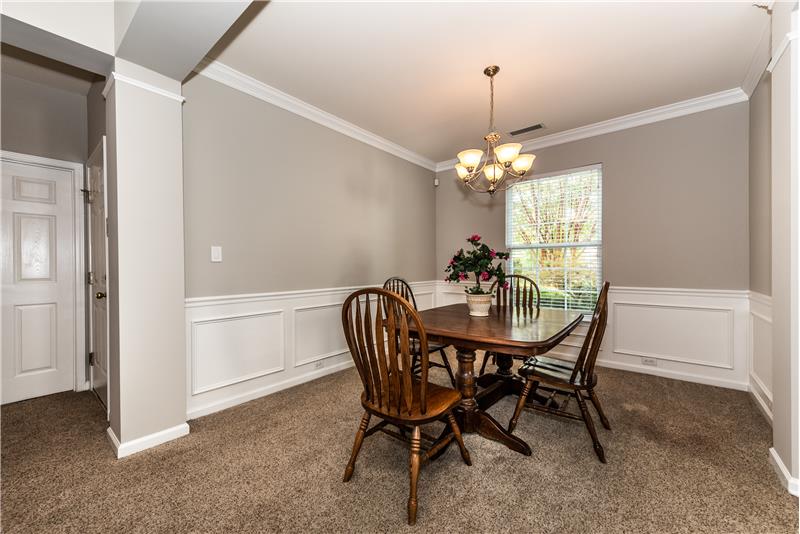 Spacious dining room with crown molding and wainscoting; neutral paint.