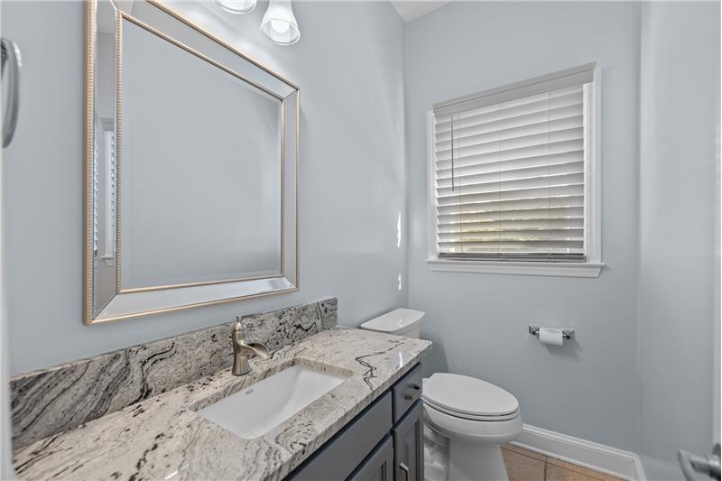 Powder room updated in 2019 with granite counter, rectangular sink, light fixture, mirror.