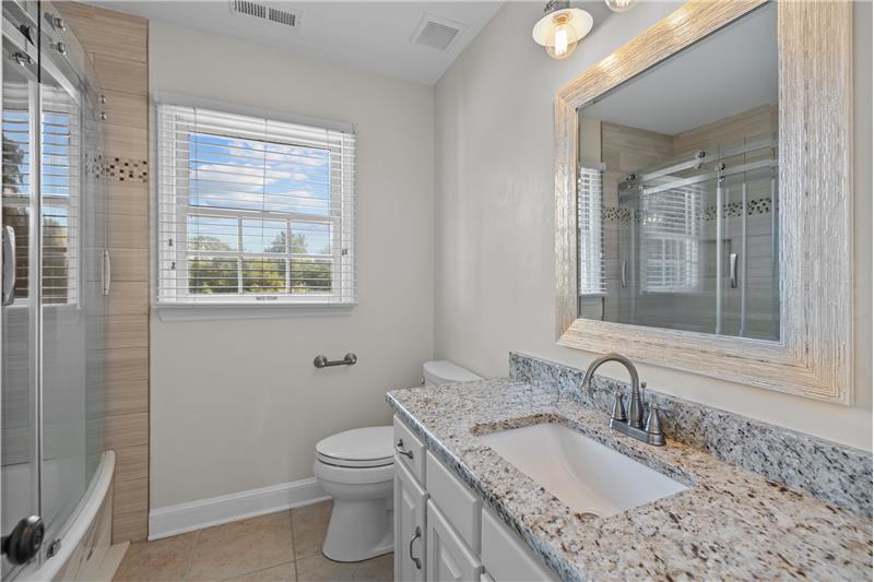 Bathroom shared by the secondary bedrooms. Granite counter, updated mirror and light fixtures.
