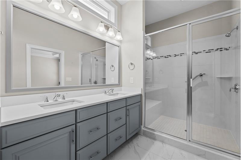 Primary Bathroom: en-suite owner's bathroom with oversized shower with seat, tile surround, marble tile floors.