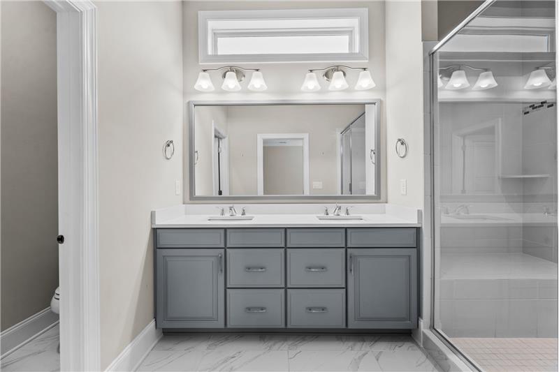 Primary Bathroom: features dual sink, raised vanity with quartz counter, transom window, private water closet.