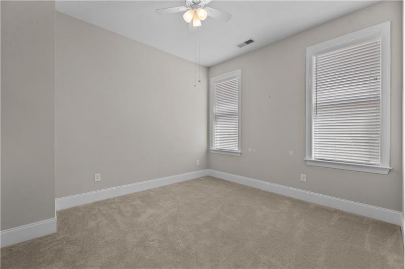 Secondary Bedroom #1: features neutral carpet, paint, faux wood blinds, ceiling fan with light.