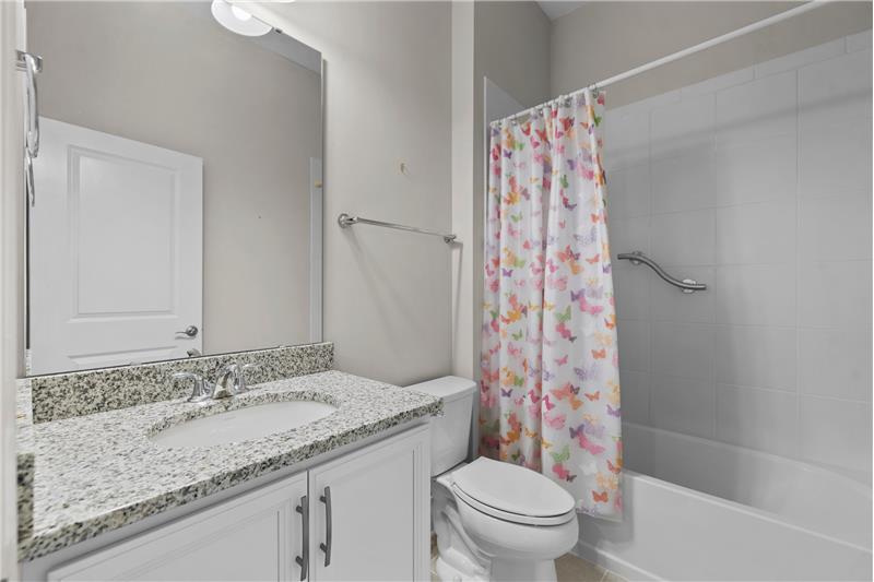 Guest Bath: features raised vanity with granite counter, tile floors, tub/shower with tile surround.
