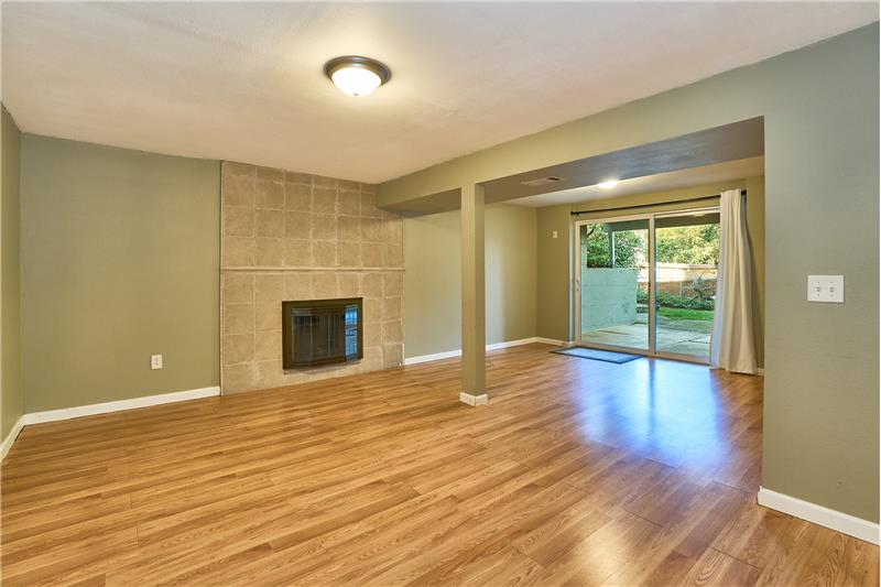 Huge Downstairs Recreational Room with Hardwood Laminate Flooring and Tile Surround Wood Burning Fireplace.