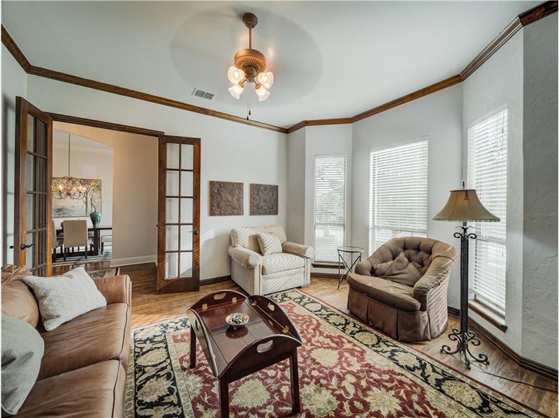 Office/formal Living room featuring ceiling fan with notable chandelier, french doors, crown molding, and light wood-type floor