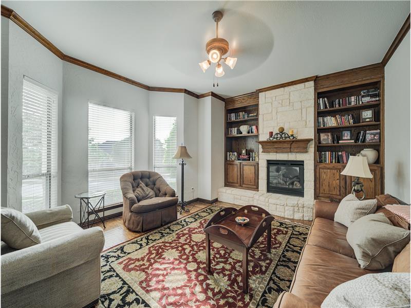 Office/Formal Living room featuring a stone fireplace, ceiling fan, light wood-type flooring, built in shelves