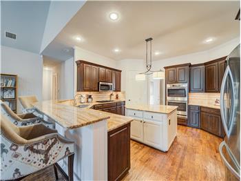 Kitchen with appliances with stainless steel finishes, a kitchen island, backsplash, light hardwood / wood-style floors