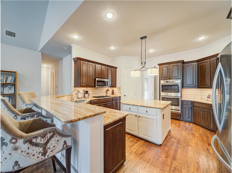 Kitchen with appliances with stainless steel finishes, a kitchen island, backsplash, light hardwood / wood-style floors