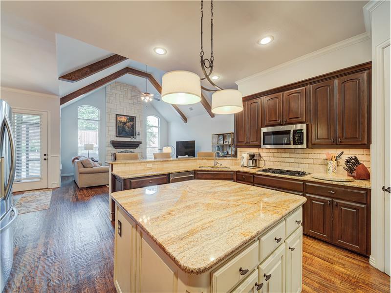 Kitchen featuring hanging light fixtures, stainless steel appliances, lofted ceiling with beams, hardwood floors & center Island