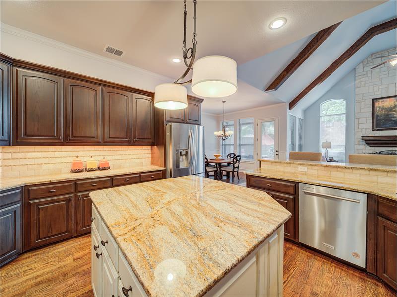 Appliances with stainless steel finishes, light hardwood / wood-style flooring, a kitchen island, hanging light fixtures