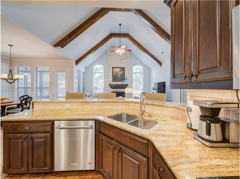 Kitchen with stainless steel dishwasher, sink, beam ceiling, and dark hardwood / wood-style floors