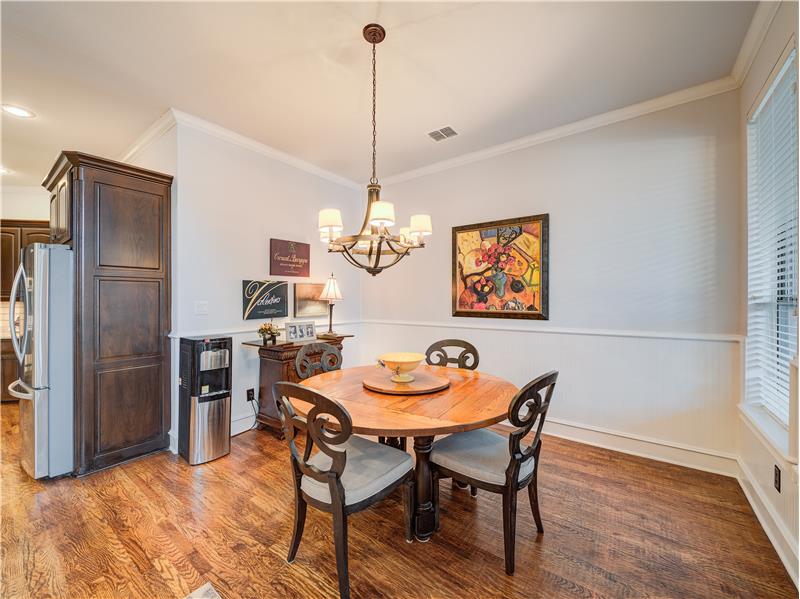 Breakfast nook space with ornamental molding, light hardwood / wood-style floors, and a chandelier