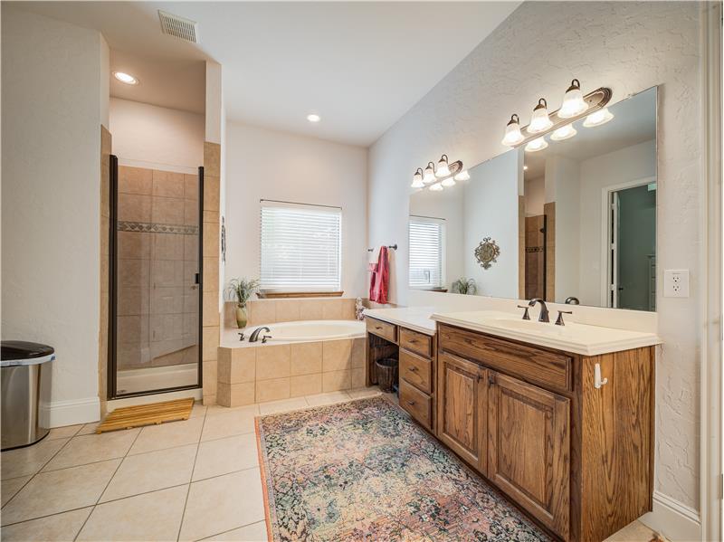 Primary bathroom featuring vanity with extensive cabinet space, tile floors, and separate shower and tub