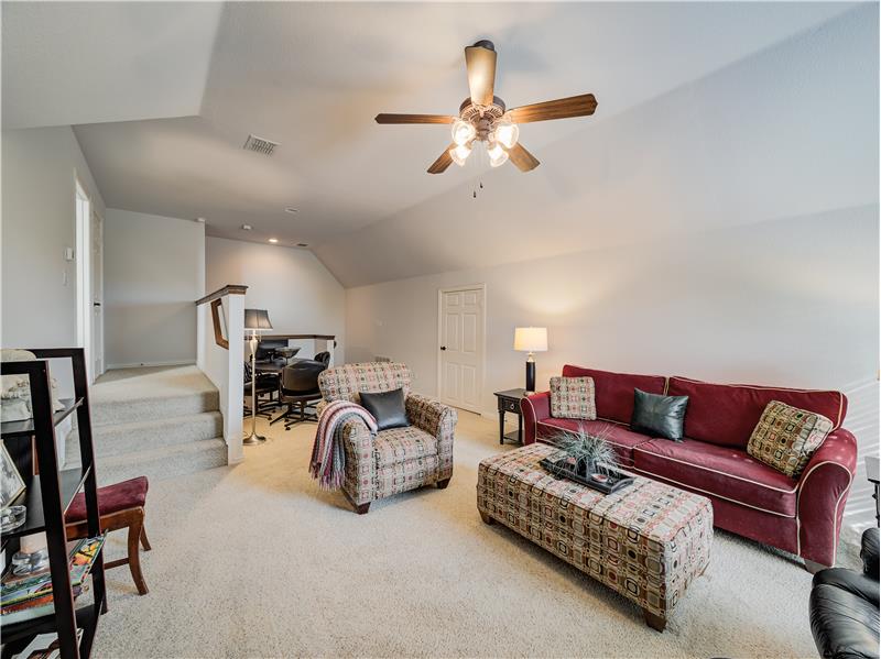 Carpeted media room with ceiling fan and lofted ceiling