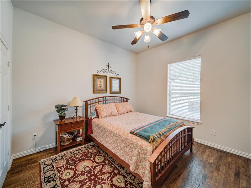 Downstairs bedroom with high ceiling, ceiling fan and hard wood flooring