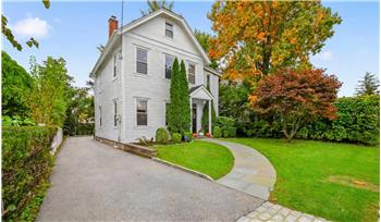Traditional two-story exterior with white lap siding, an asphalt shingle roof, a paved driveway, and a stone walkway leading to