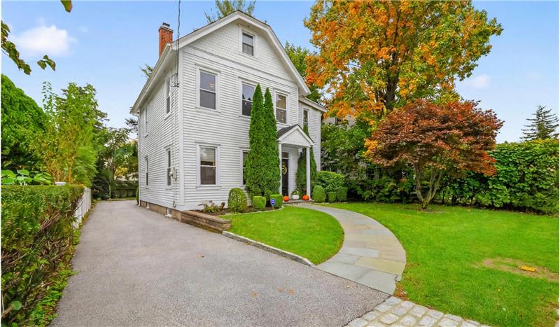 Traditional two-story exterior with white lap siding, an asphalt shingle roof, a paved driveway, and a stone walkway leading to