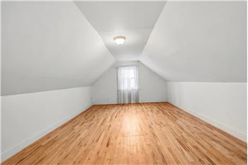 Finished loft area, Vaulted ceiling room featuring wood-finish flooring, neutral walls, and a center-mounted flush light fixture