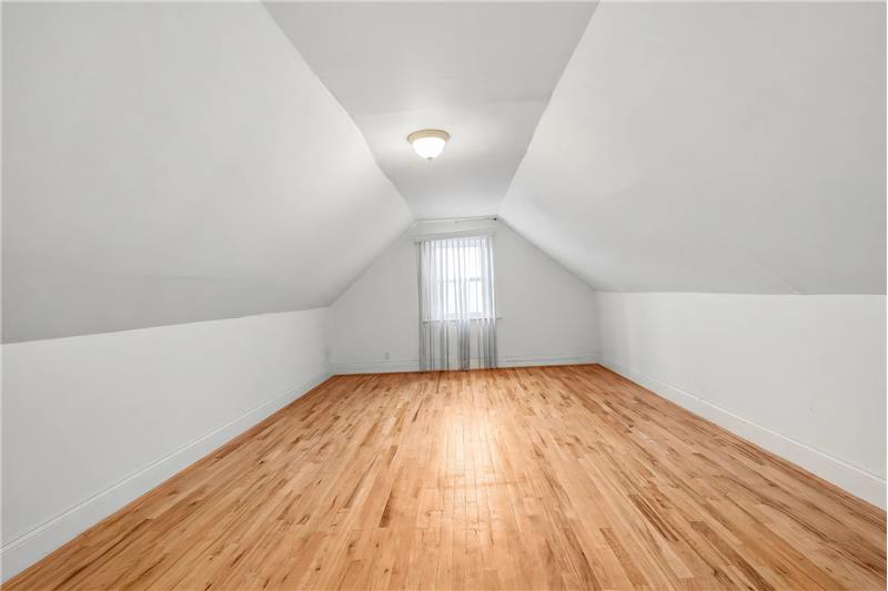 Finished loft area, Vaulted ceiling room featuring wood-finish flooring, neutral walls, and a center-mounted flush light fixture