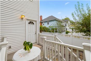 Exterior deck with white vinyl railing, horizontal lap siding, and wall-mounted sconce lighting