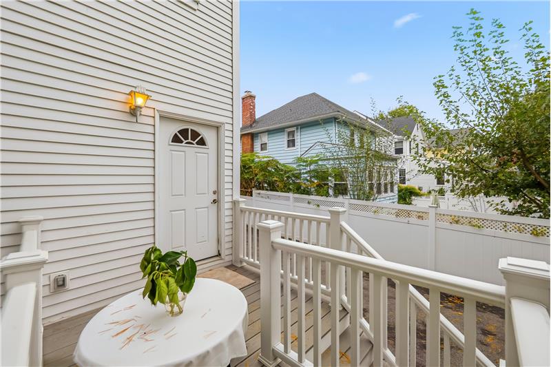 Exterior deck with white vinyl railing, horizontal lap siding, and wall-mounted sconce lighting
