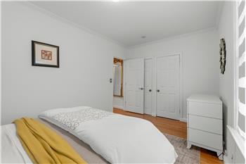 Room featuring white walls, crown molding, wood-finish flooring, and two interior six-panel doors
