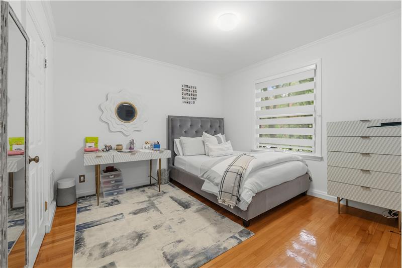 Interior room featuring wood-finish flooring, crown molding, and dual-layered window shades
