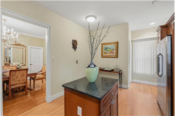 Kitchen featuring a central island with a stone countertop, wood-finish flooring, shaker-style cabinetry, and stainless steel re