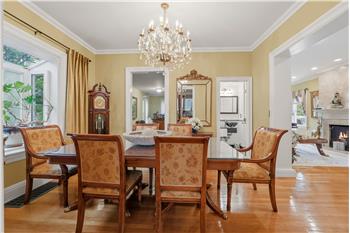Dining area featuring hardwood flooring, intricate crystal chandelier, crown molding, and bay window