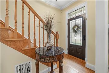 Foyer featuring natural wood-finish flooring, a solid core entry door with decorative glass inlay and transom window, and a wood